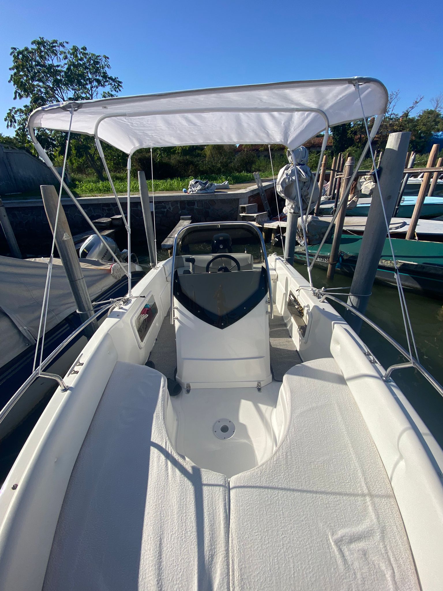 Interior of the Venetian Boat from bow to stern, with white cushions and an open canopy above the helm