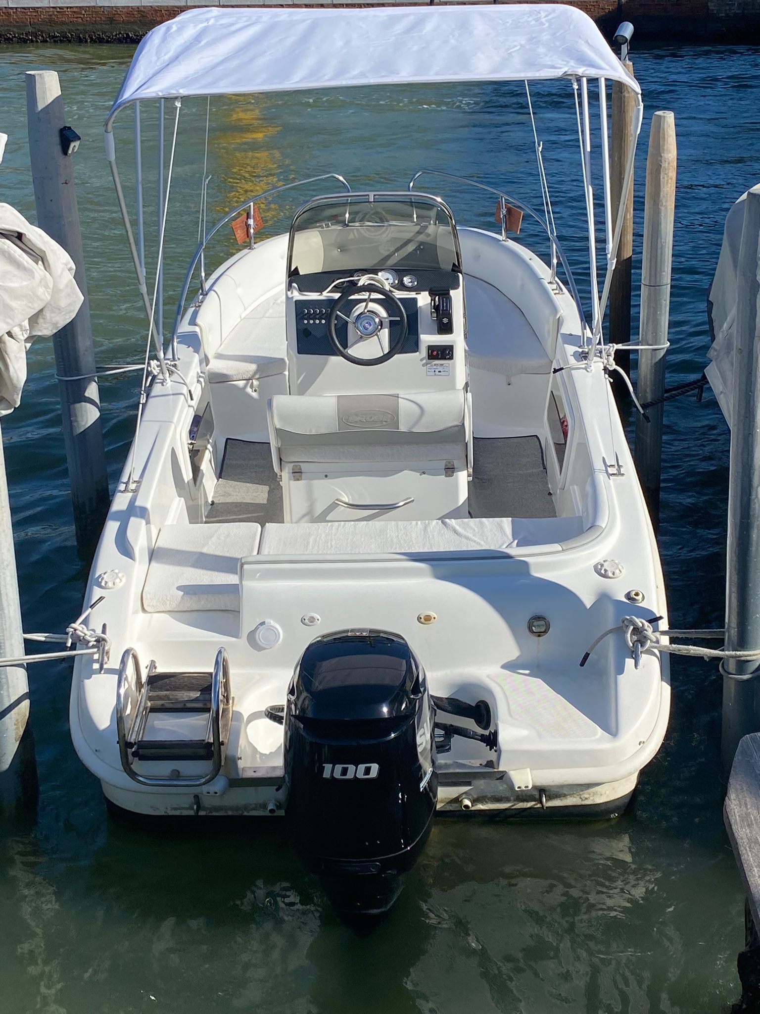 Venetian Boat seen from the stern, showing the outboard motor, ladder, seating and open white canopy