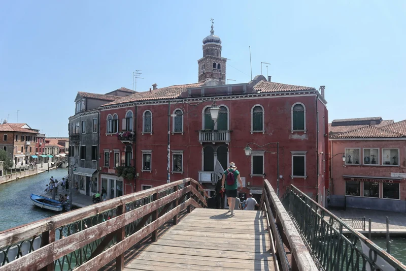 A bridge, canal and historic buildings in Murano on a sunny day