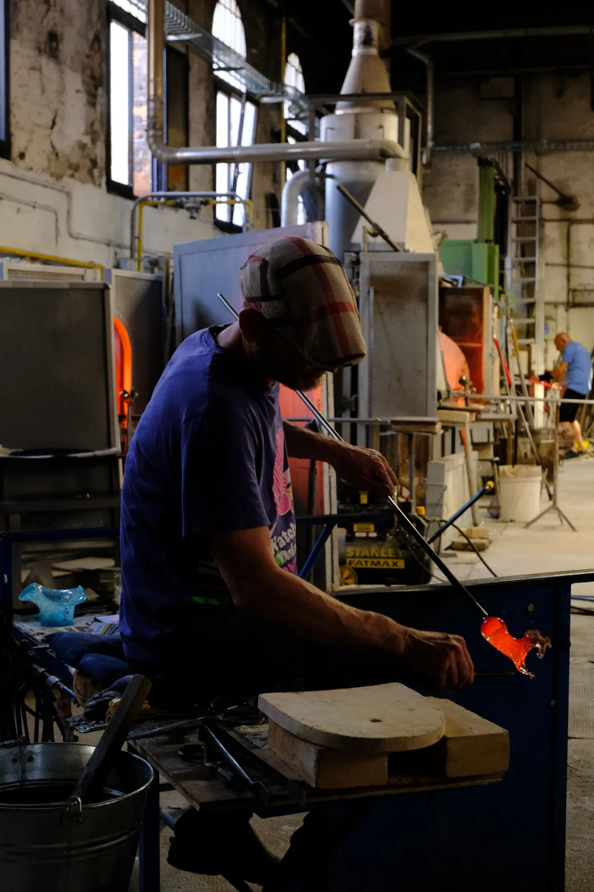 A glassmaker shaping molten glass in a Murano workshop; illustrative photograph