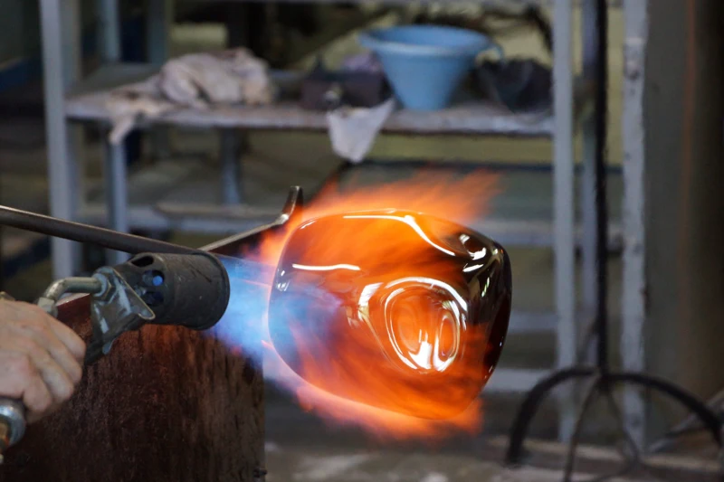 A glass object being worked in a flame; illustrative photograph, not of the factory visited